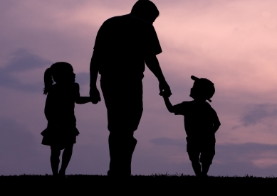 Silhouette of father and two kids