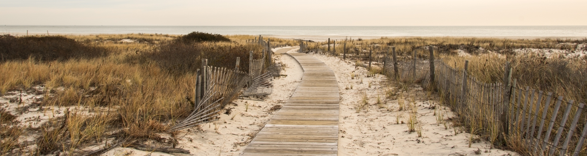 Image of wood walkway up to beach with ocean in the background