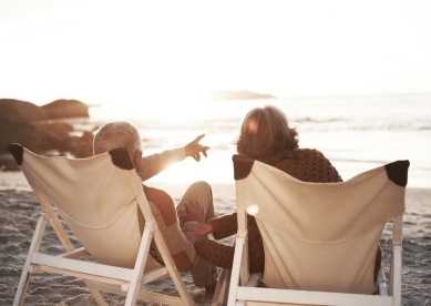 Senior couple sitting on beach looking out at the ocean